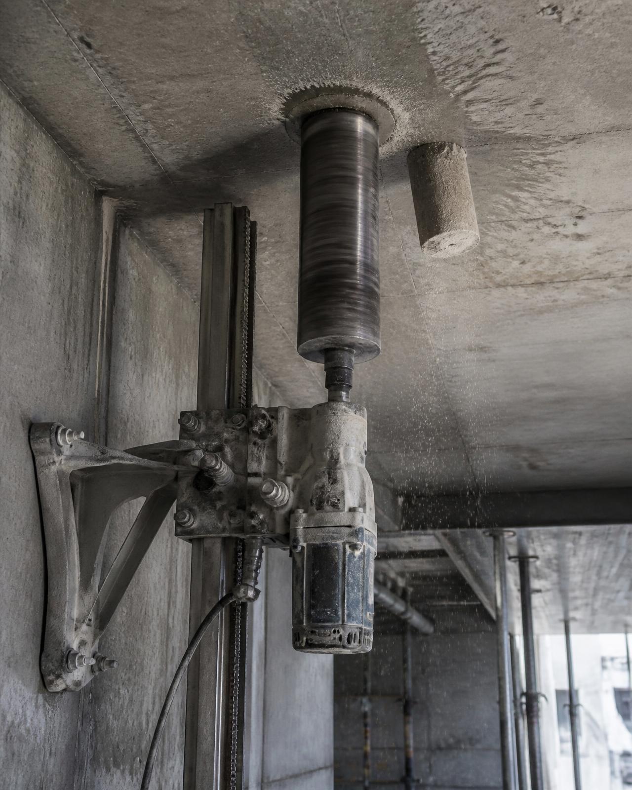 Kernbohrgerät mit Stativ an einer Betondecke, ausgebohrter Bohrkern